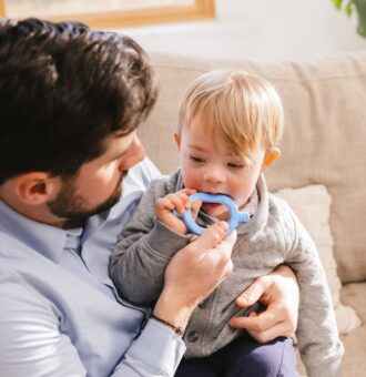 Tată ghidând bebelușul în utilizarea ARK Baby Grabber – instrument de explorare orală și masticație timpurie recomandat de logopezi și terapeuți ocupaționali