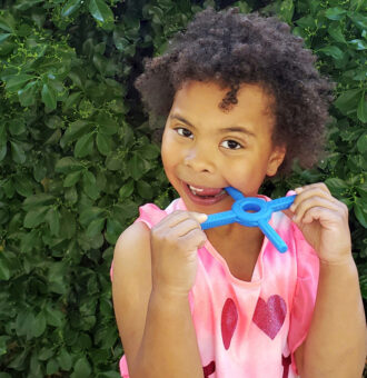 Copil folosind ARK Tetra-Bite instrument de masticatie albastru pentru logopedie